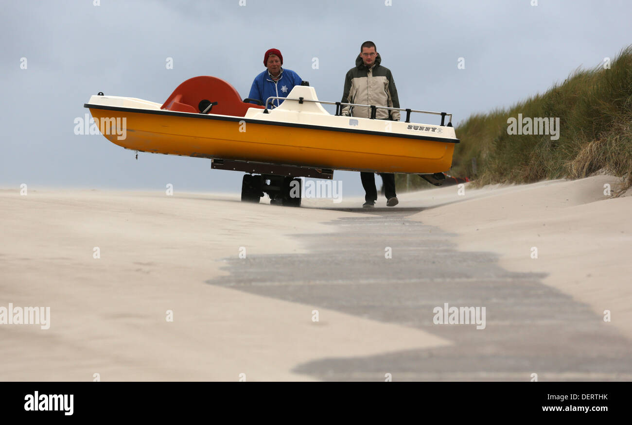 A wicker-beach-chair-hirer and a helper take a pedal boat to its winter quarters at the Baltic Sea beach of Warnemuende, Germany, 23 September 2013. Photo: Bernd Wuestneck Stock Photo