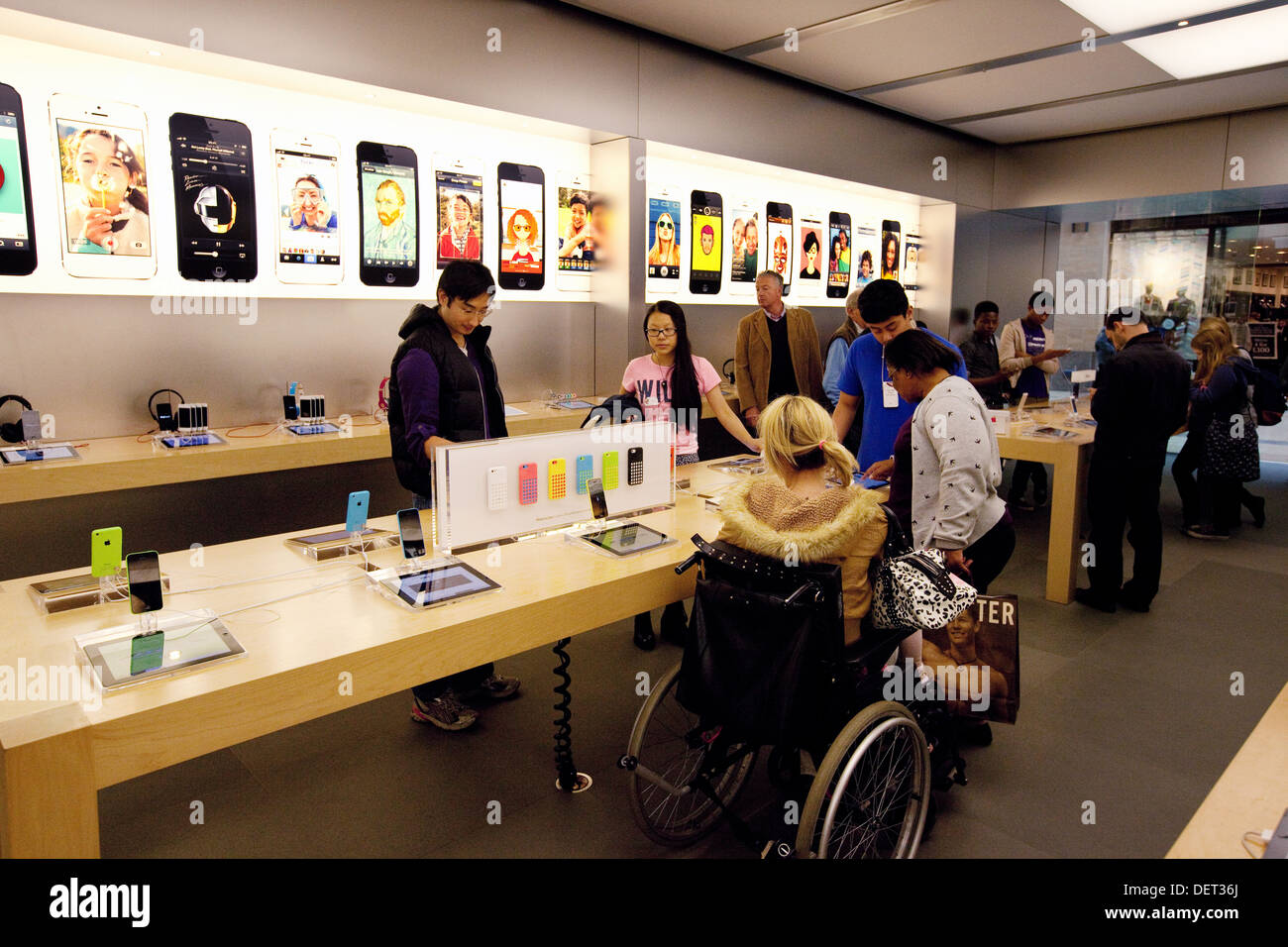 Disabled woman in a wheelchair shopping in the Apple store, Grand Arcade, Cambridge UK Stock Photo