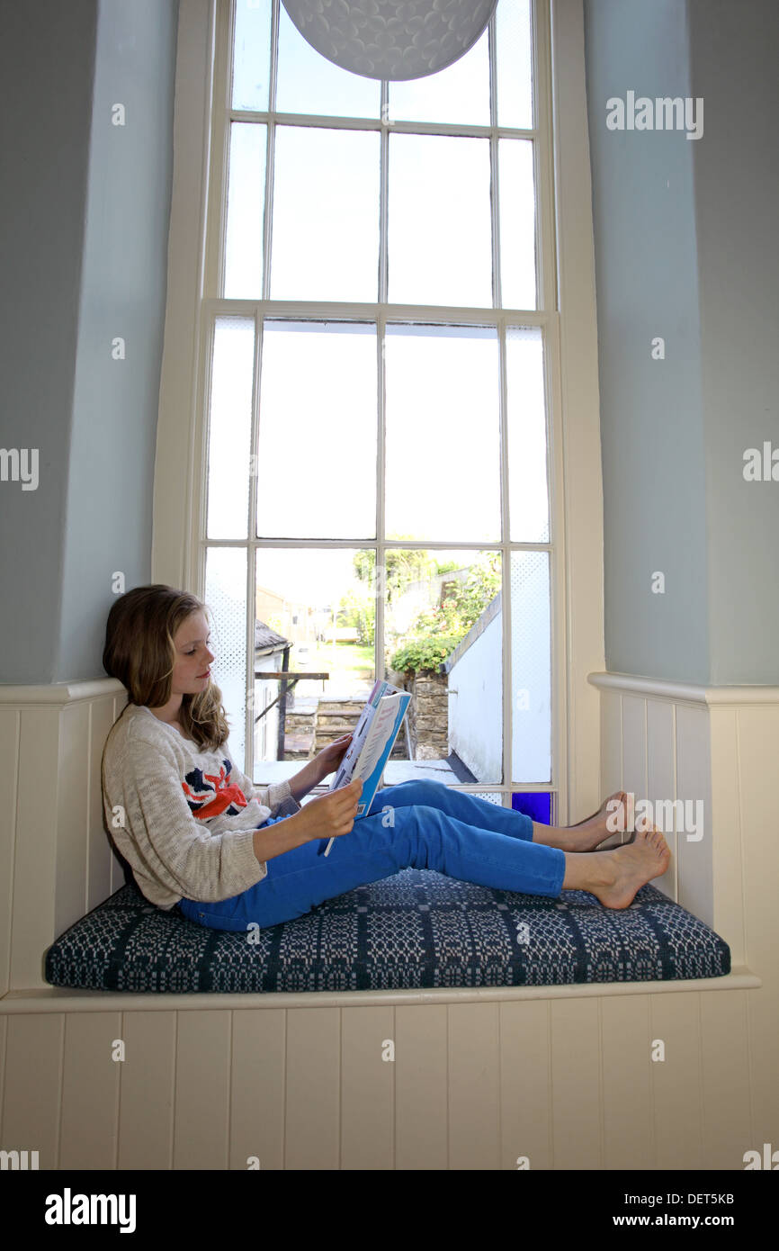 girl reading in a window seat Stock Photo