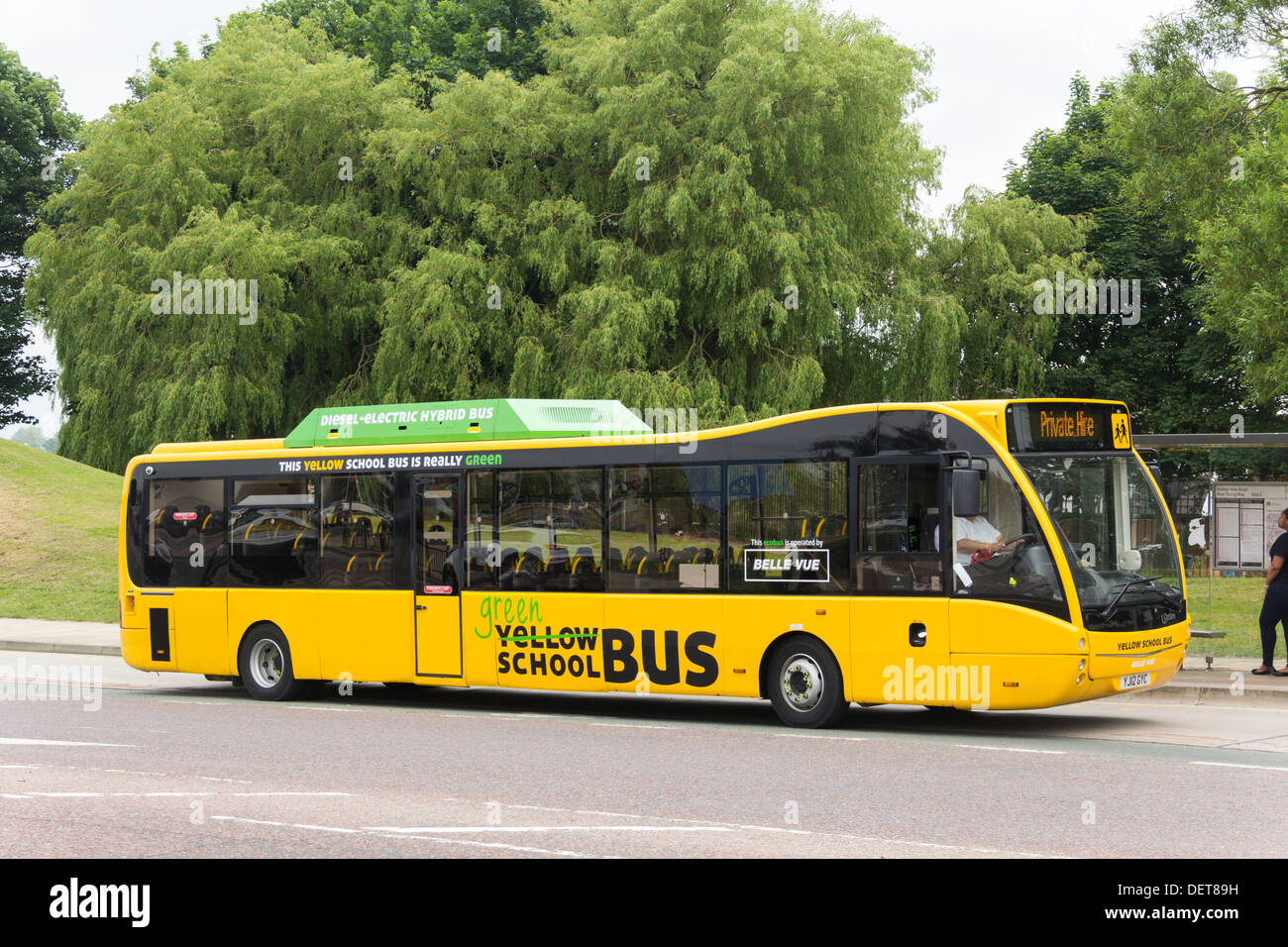 A yellow school bus (UK variety) in Manchester. The vehicle is an Optare Versa Hybrid low diesel/electric emission vehicle. Stock Photo