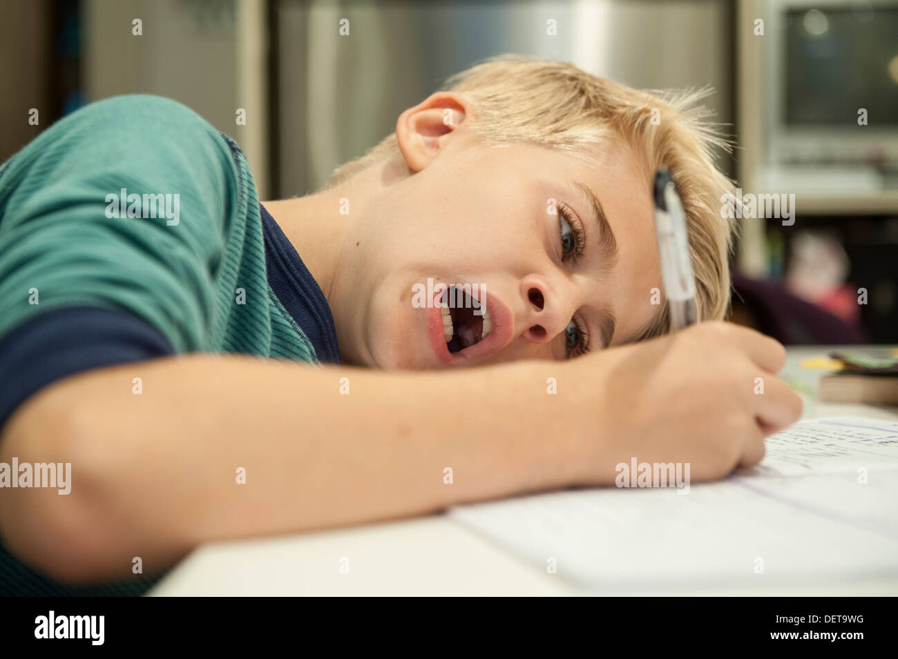 A child yawns whilst doing his homework Stock Photo