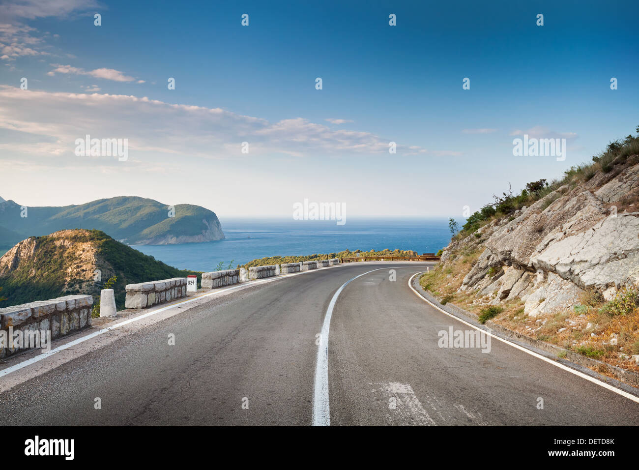 Right turn of mountain highway with blue sky and sea on a background Stock Photo
