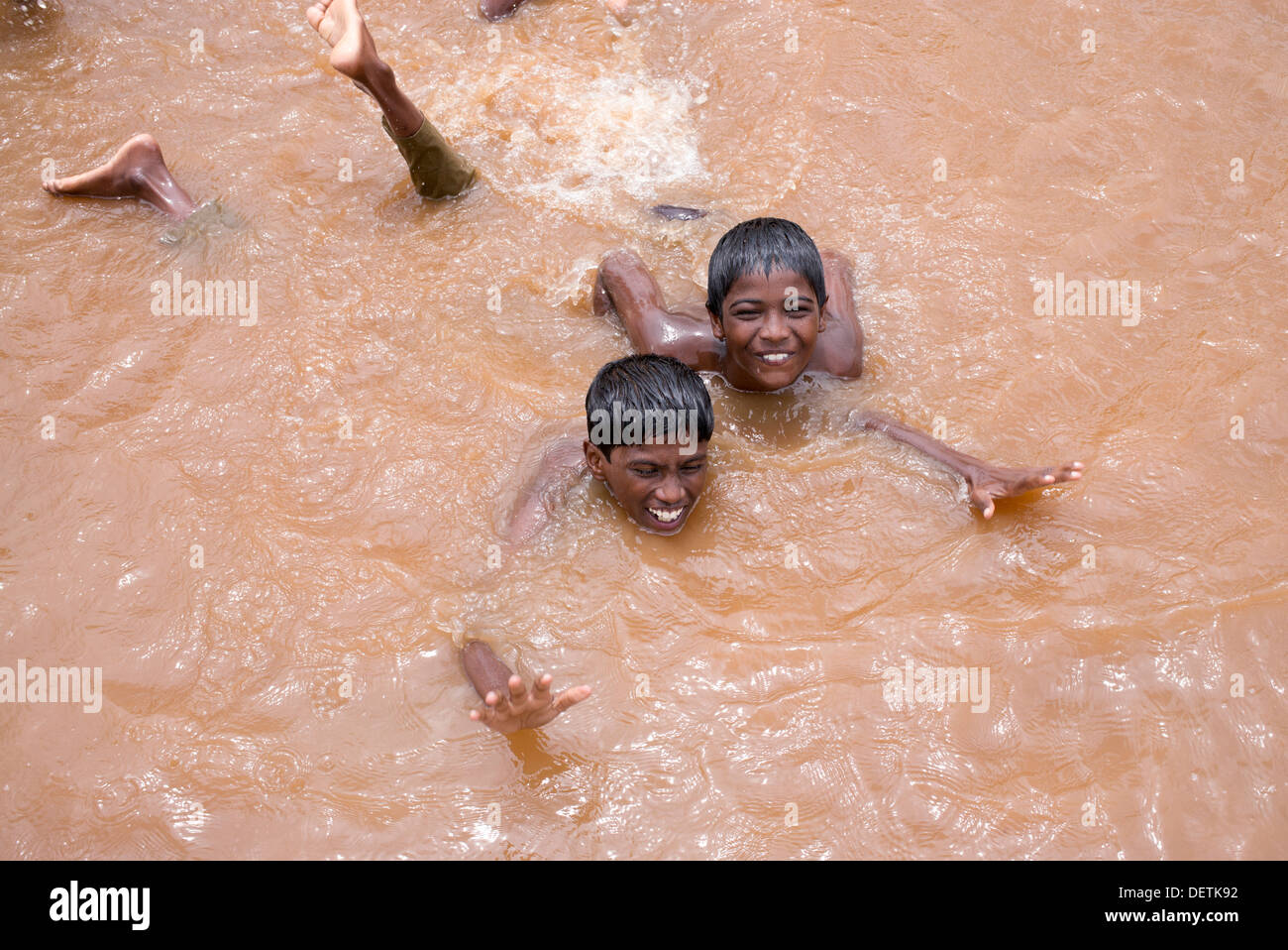 Rural Indian village boys playing and messing about in a flooded river. Andhra Pradesh, India Stock Photo
