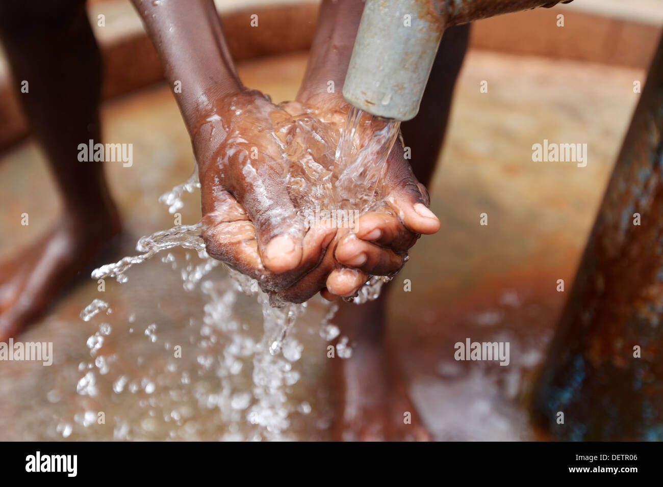 A young boy collects clean water pumped by an NGO funded well beside his village in the Lira district of northern Uganda. Stock Photo