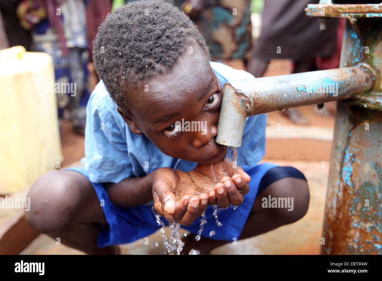 A young boy collects clean water pumped by an NGO funded well beside his village in the Lira district of northern Uganda. Stock Photo