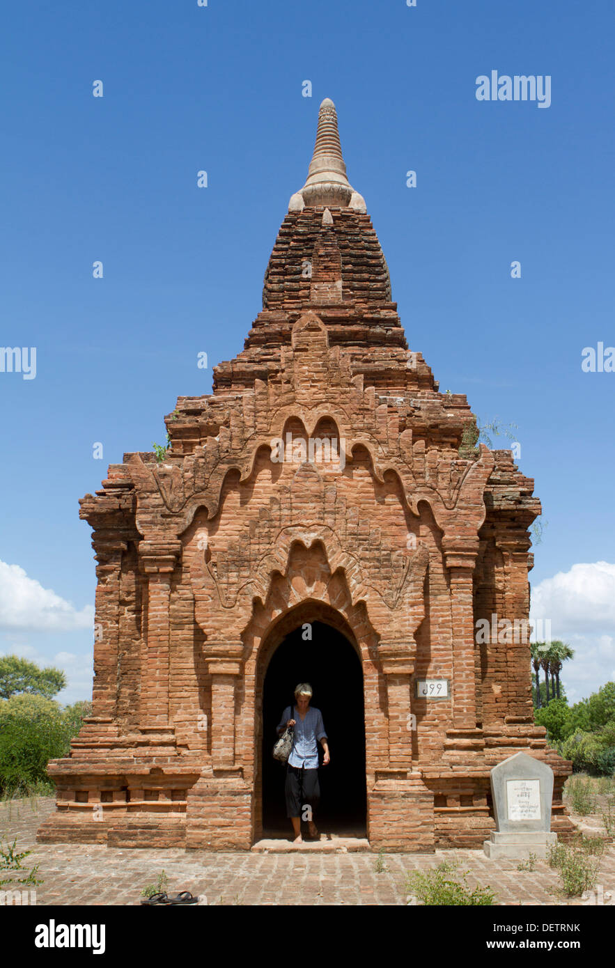 A woman walks out of a small temple in the North Plain of Bagan. Stock Photo