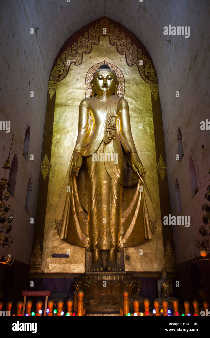 People walk past a a buddha image in a temple in Bagan. Stock Photo