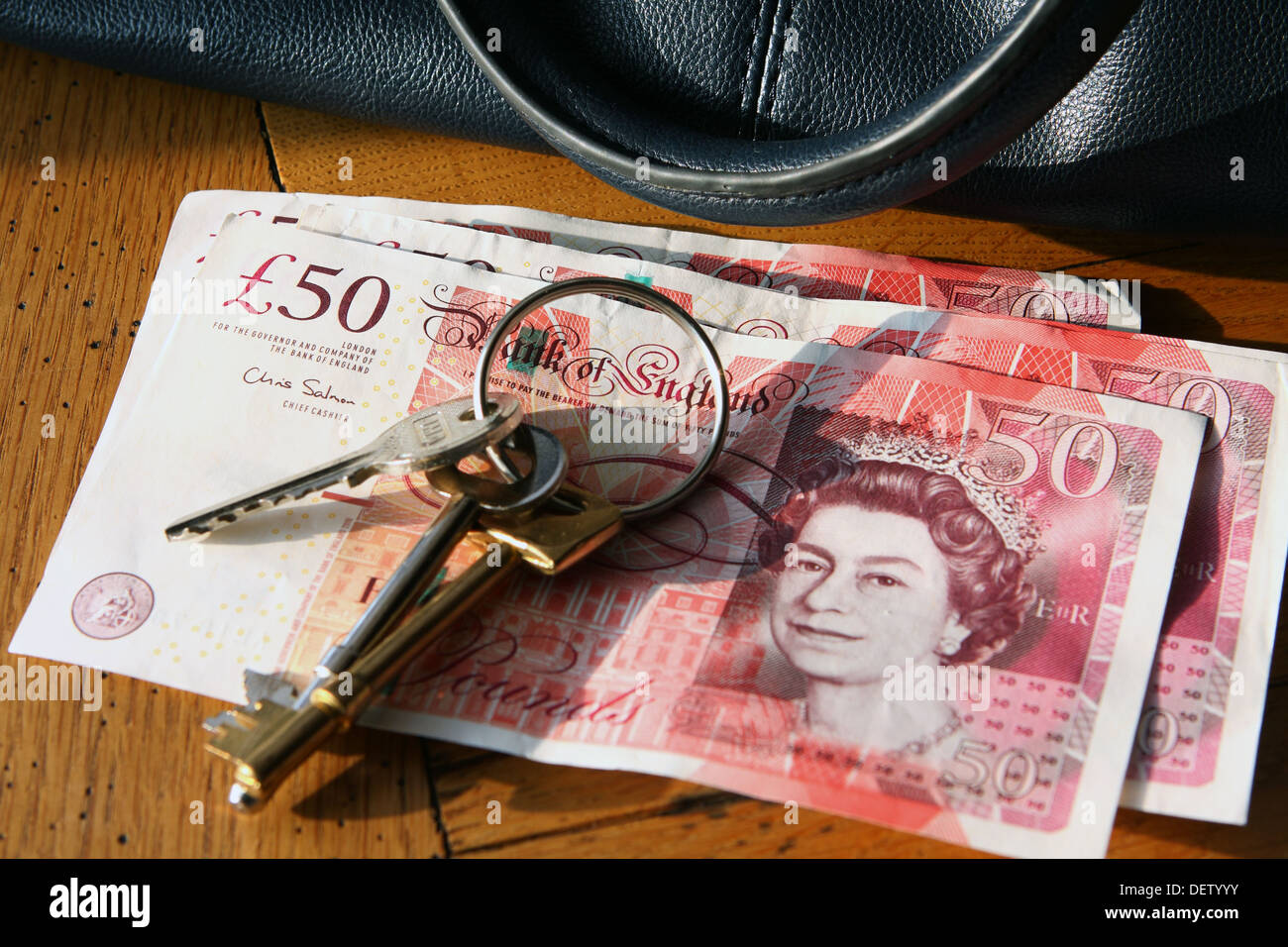 A bunch of keys on sterling £50 notes next to a handbag Stock Photo