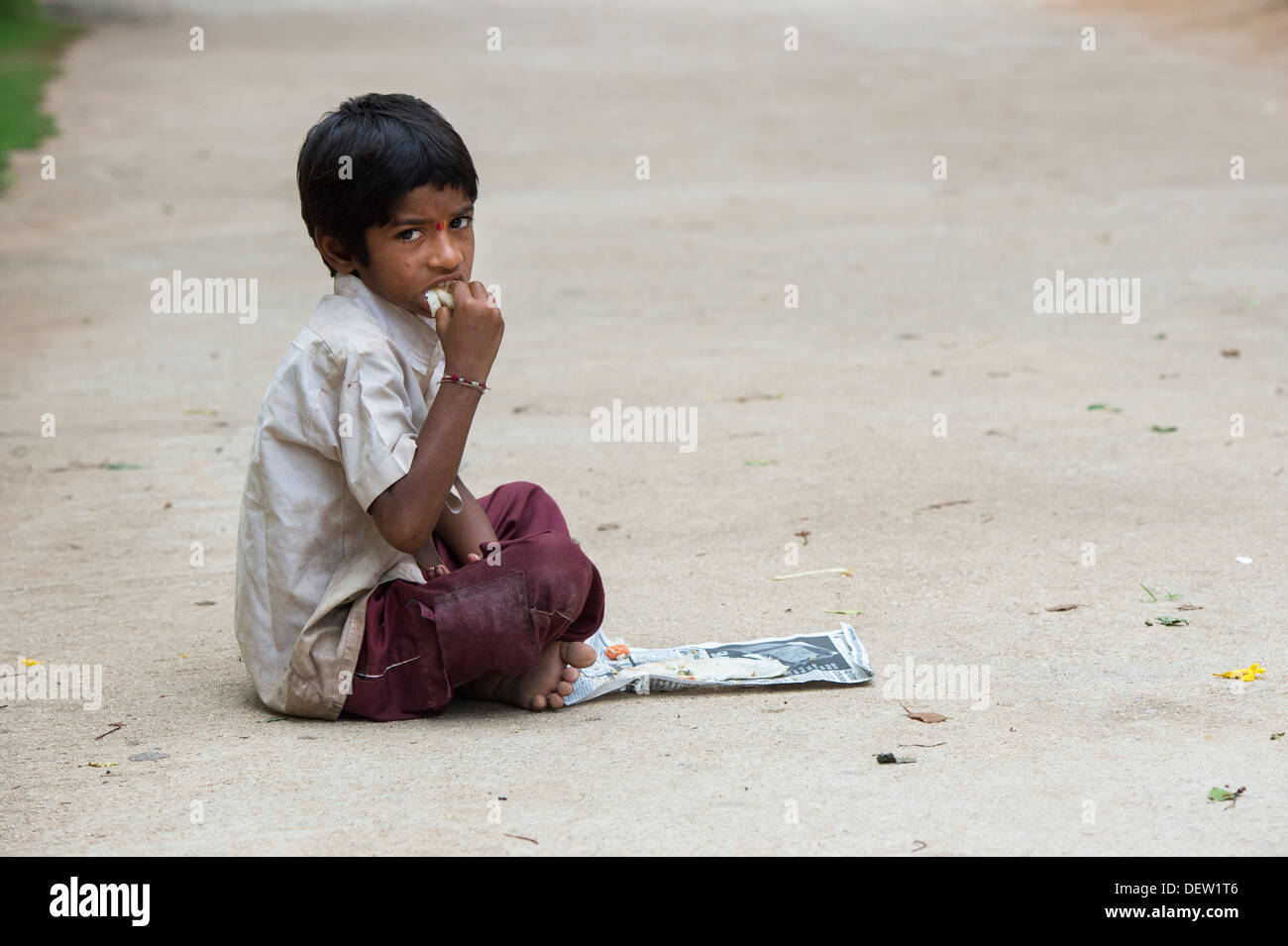 Indian lower caste boy eating dosa for breakfast on an Indian street. Andhra Pradesh, India. Copy space Stock Photo