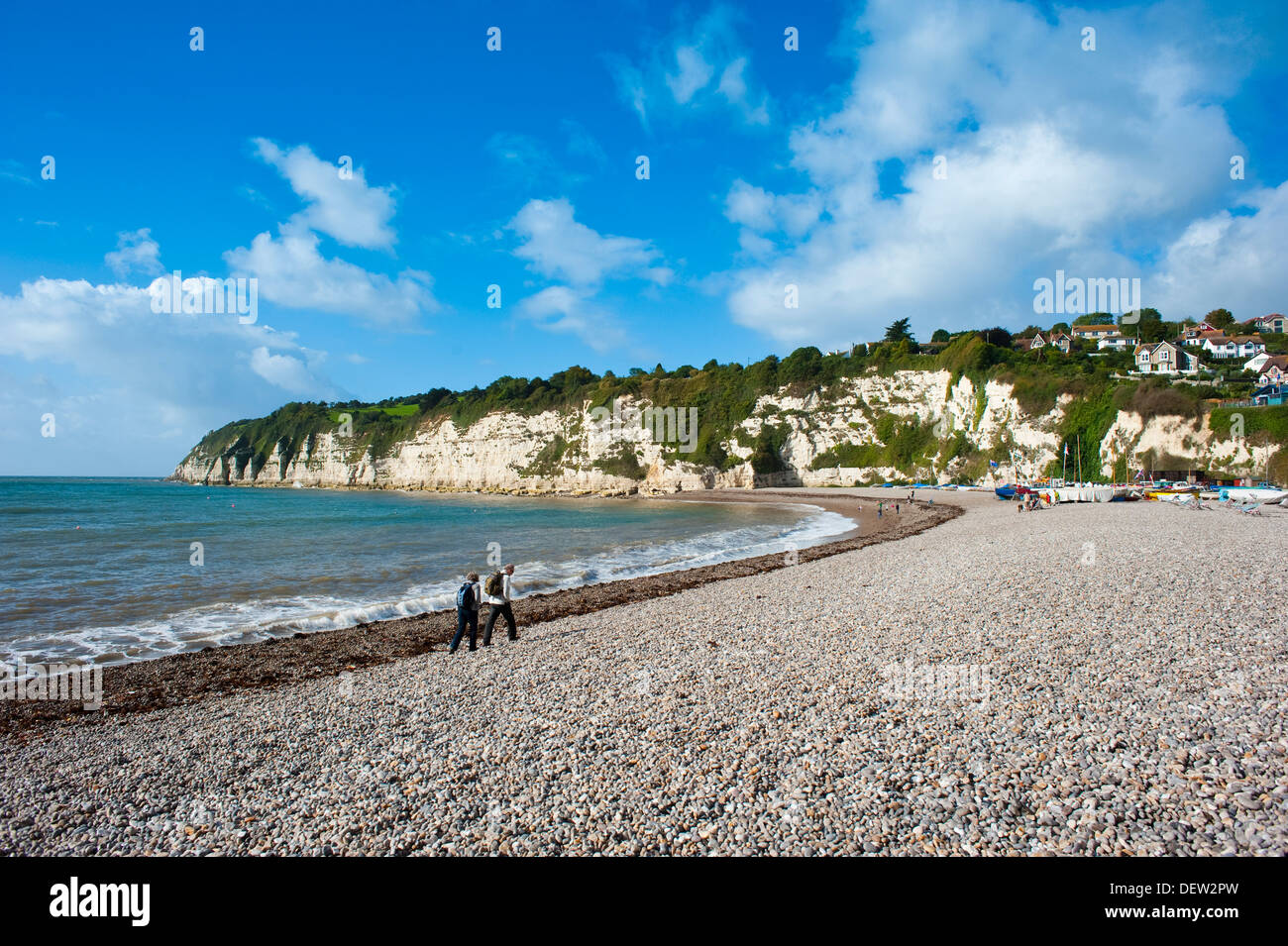 Two people walking on shingle beach on Jurassic coast at Beer, Devon, England, UK Stock Photo