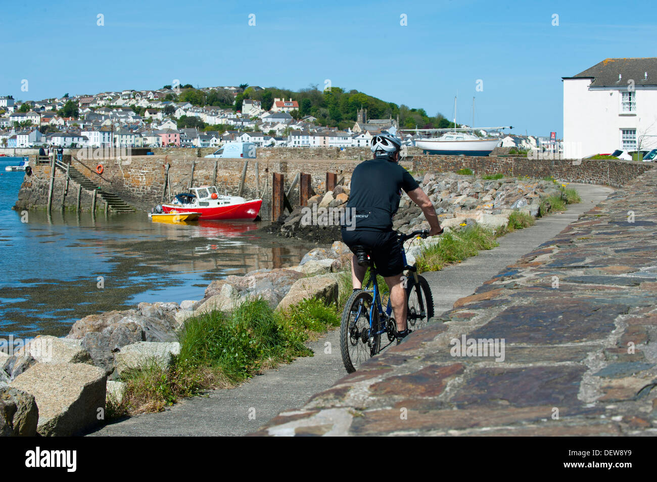 A male cyclist pedals into Instow in North Devon beside the Taw Torridge estuary and Appledore Stock Photo