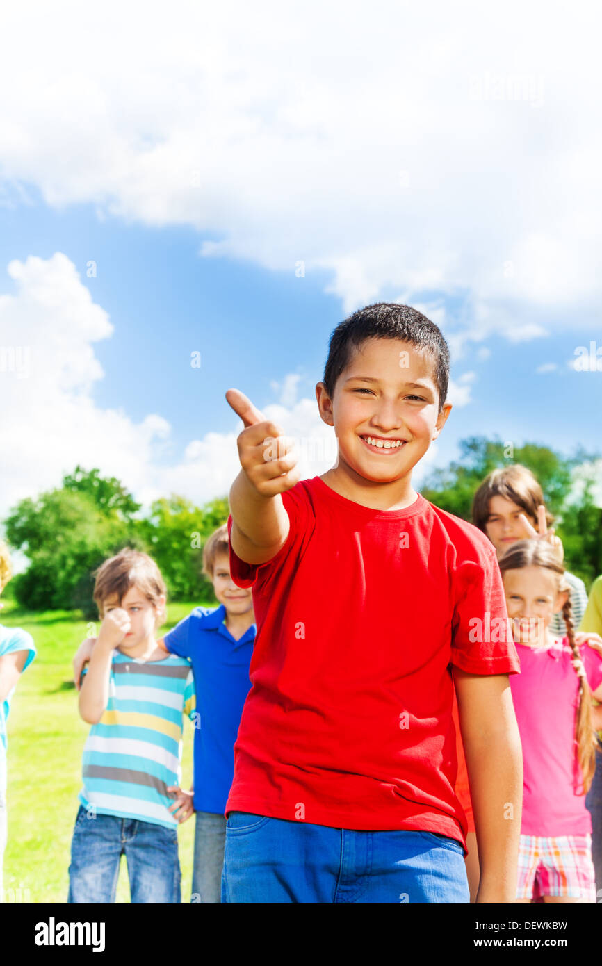 Happy smiling Asian boy showing thumb up thumb with group of kids on background Stock Photo