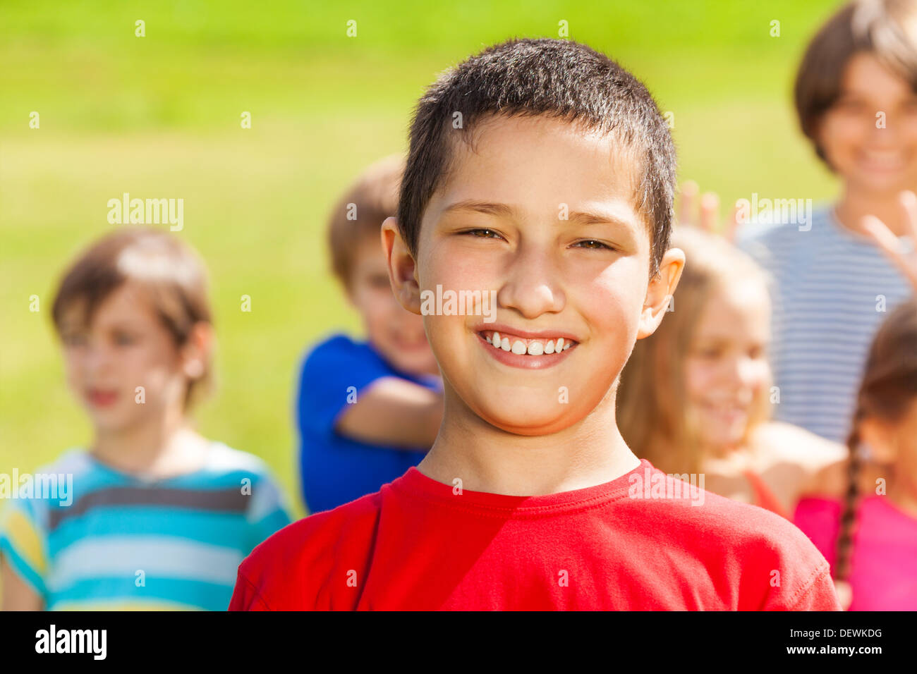 Close portrait of Asian boy with big happy smile and group of friends on background Stock Photo