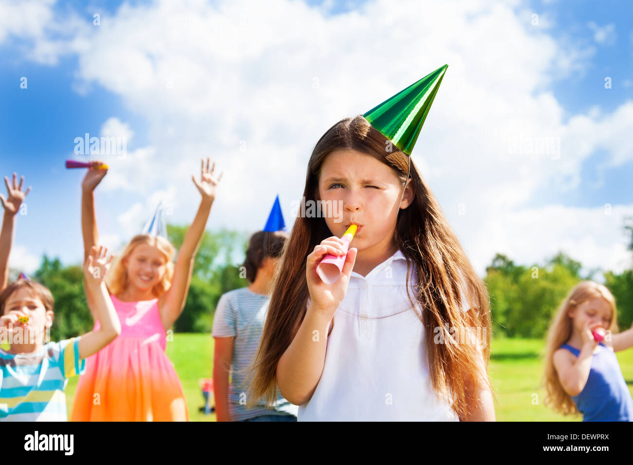Cute little girl child blow noisemaker on a birthday party wearing cap