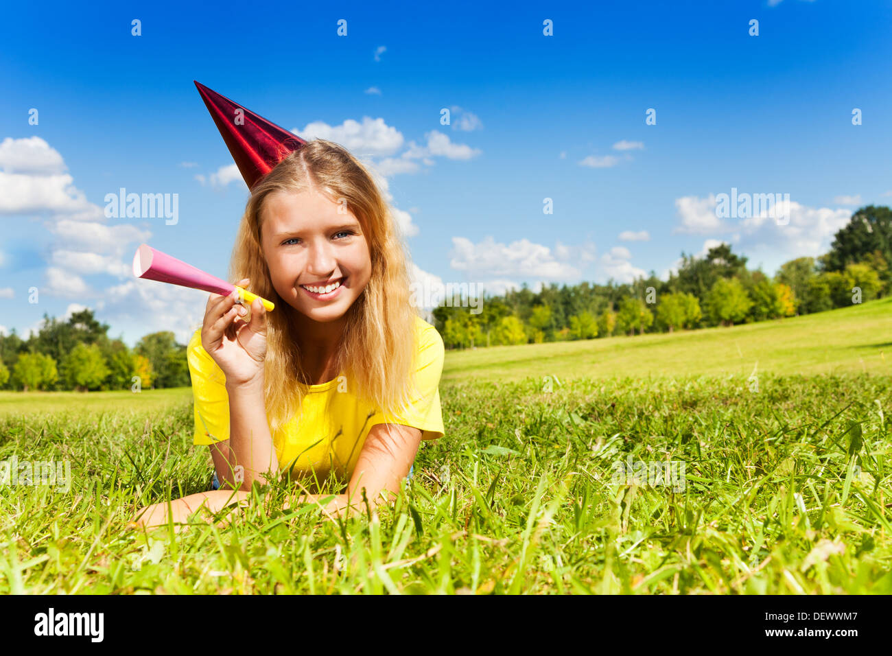 Portrait of teen little girl with noisemaker horn and birthday party ...