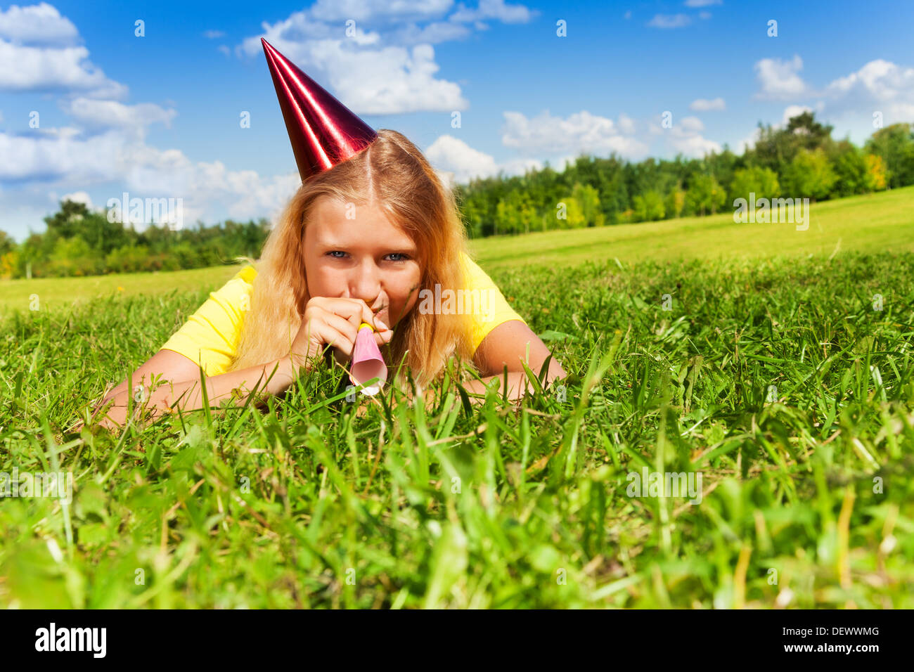 Beautiful teen girl with noisemaker horn and birthday party cap laying