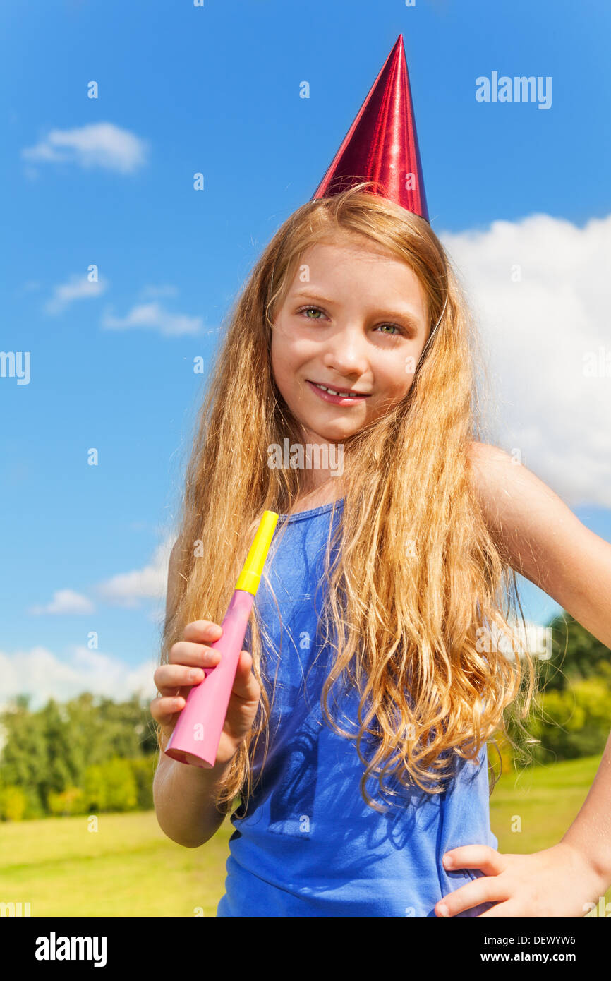 Beautiful little girl with noisemaker horn and birthday party cap