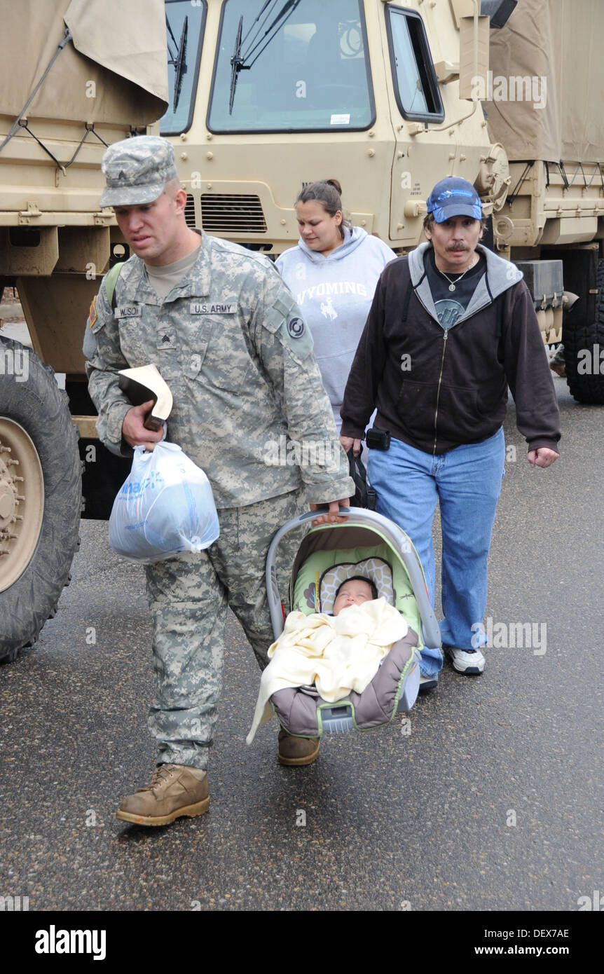 Colorado Army National Guard Sgt. David Wilson, 1st Battalion 157th Forward Support Company, escorts Thomas Walter and Melinda Villa while carrying Ezra Villa to the flood evaluation area in Lyons, Colo. Sept. 13, 2013. The CONG is assisting Boulder Count Stock Photo