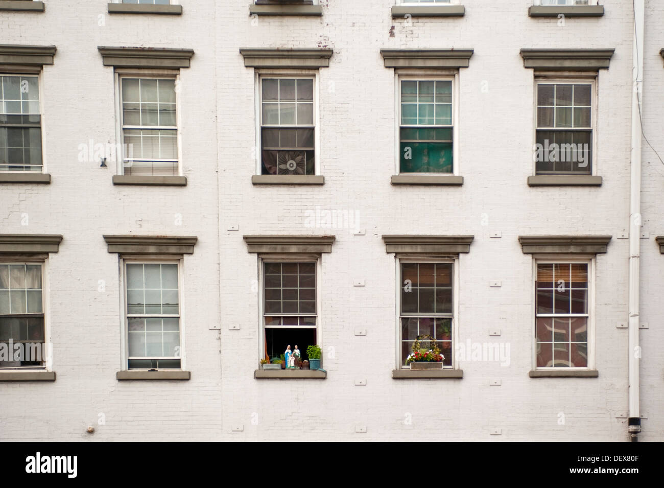 A straight on facade view of an old apartment building in New York City showing rows of windows with religious statues on the Stock Photo