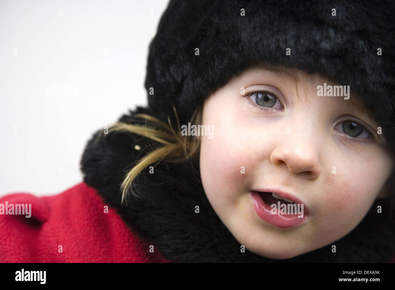 3 years old girl in red coat with fur collar, cuffs and hat against