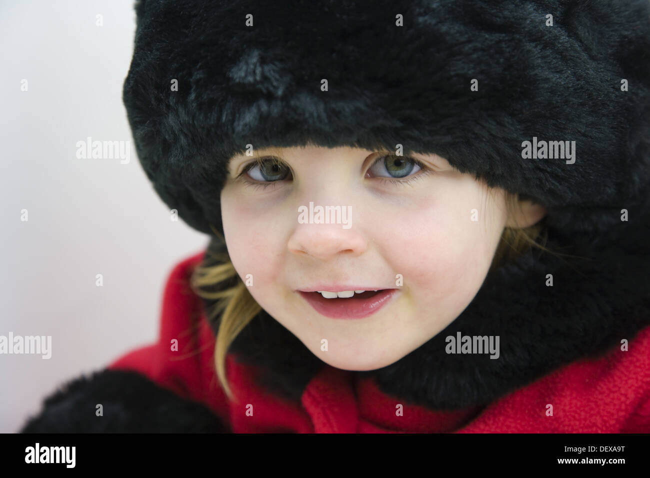 3 years old girl in red coat with fur collar, cuffs and hat against