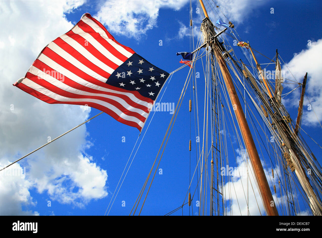 An American Flag, Mast And Rigging Against A Deep Blue Cloudy Sky