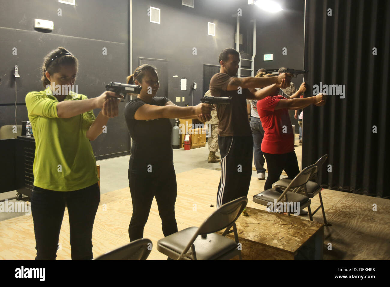 Spouses of Marines with 7th Engineer Support Battalion, 1st Marine Logistics Group, practice their shooting skills in the Indoor Simulated Marksmanship Trainer during Jane Wayne Day, Sept. 13, 2013. The event gave spouses a chance to learn more about the Stock Photo