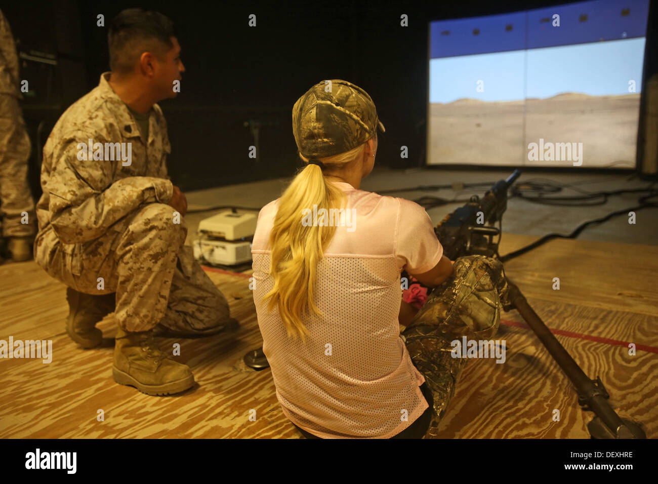 The wife of a Marine with 7th Engineer Support Battalion, 1st Marine Logistics Group, practices her shooting skills in the Indoor Simulated Marksmanship Trainer during Jane Wayne Day, Sept. 13, 2013. The event gave spouses a chance to learn more about the Stock Photo