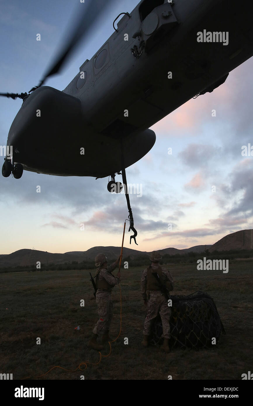 Marines with Landing Support Company, Combat Logistics Regiment 17, 1st Marine Logistics Group, attach cargo to the bottom of a Stock Photo