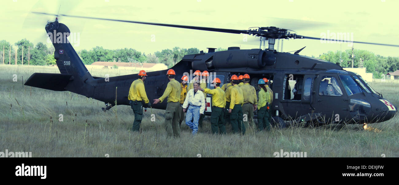 Evacuees exit a UH-60 Black Hawk helicopter assigned to the Wyoming Army National Guard, with the assistance of the USDA Roosevelt Hotshots at Christman Field in Fort Collins, Colo., Sept. 16, 2013. Colorado and Wyoming National Guard units were activated Stock Photo