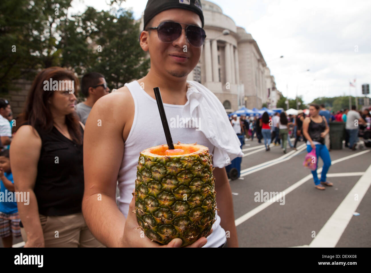 Man holding up a Piña Colada cocktail in pineapple at outdoor festival - USA Stock Photo