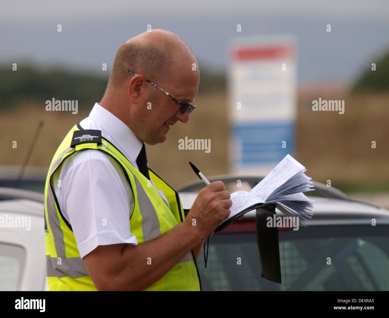 Civil Enforcement Office / Traffic warden writing in his notebook before giving a parking ticket, Exmouth, Devon, UK 2013 Stock Photo