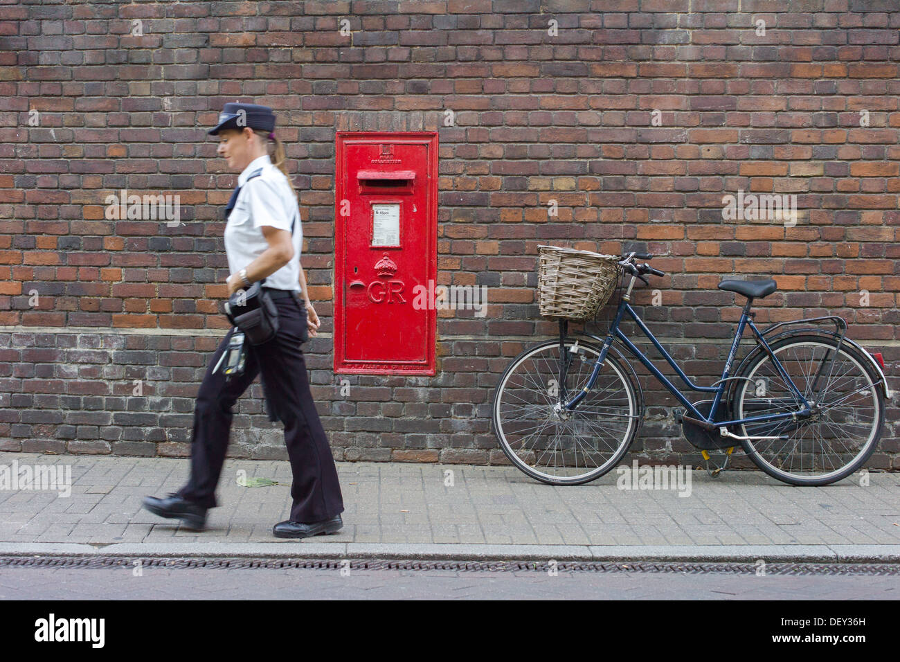 Bike and post box with traffic warden passing Stock Photo