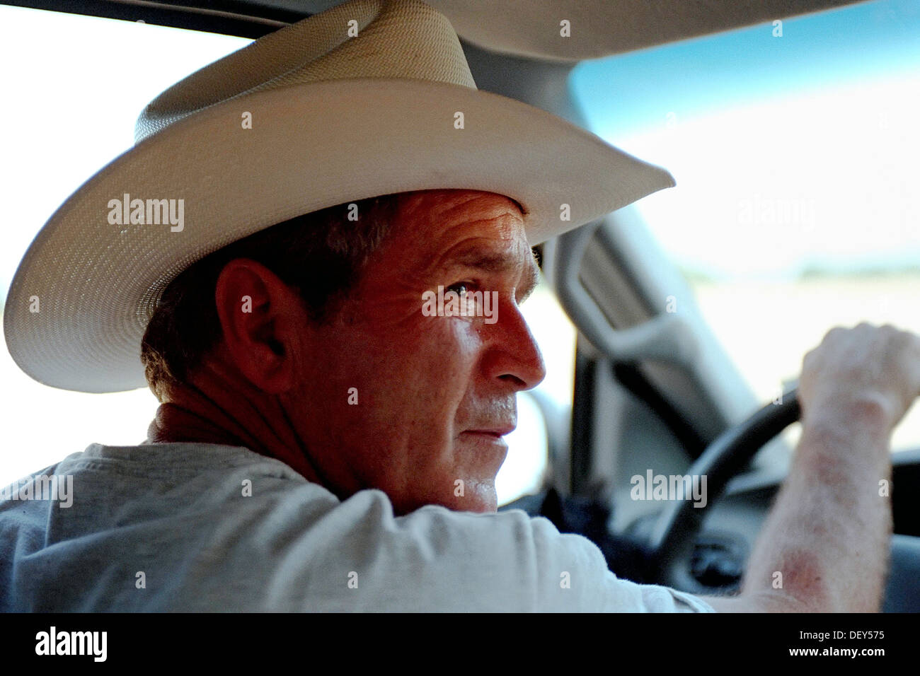 US President George W. Bush drives his pickup truck wearing a cowboy hat at his ranch August 9, 2002 in Crawford, Texas. Stock Photo