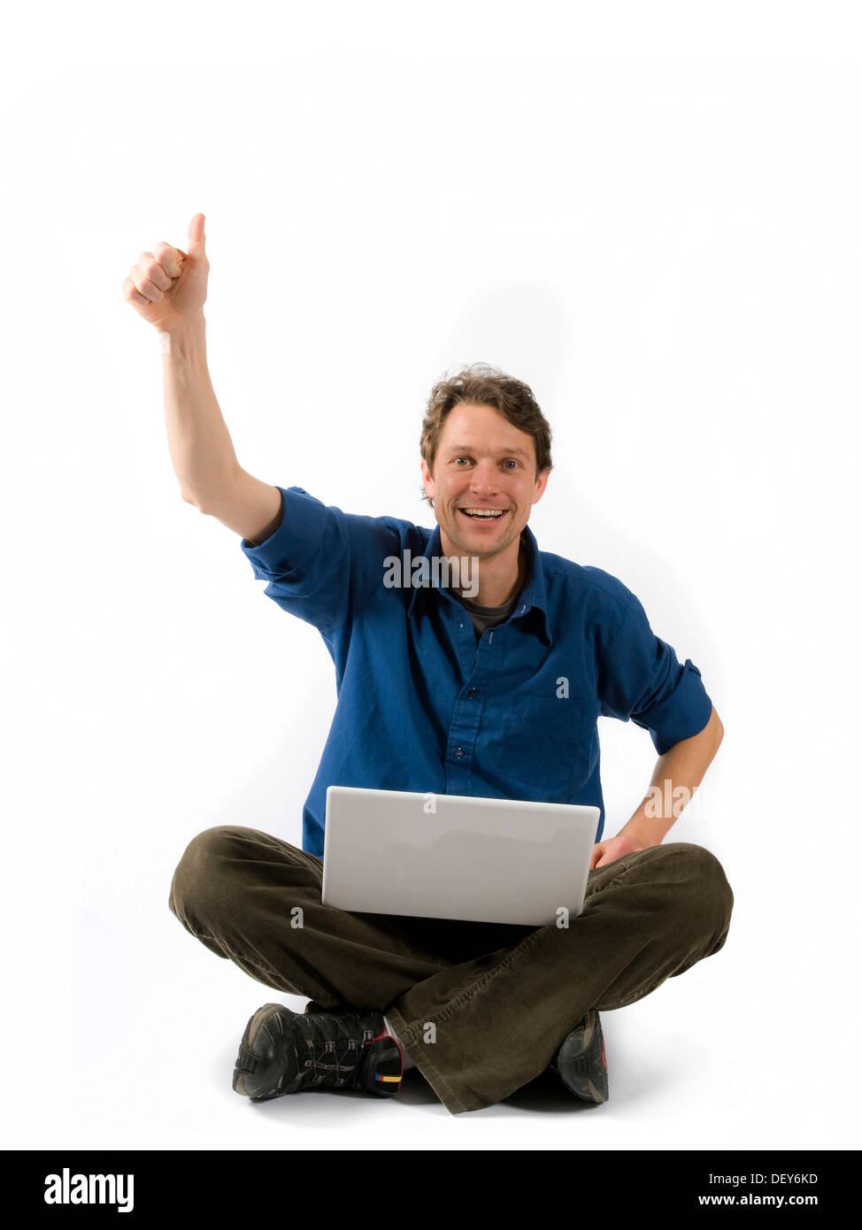 Cheering man with laptop sitting cross-legged Stock Photo - Alamy