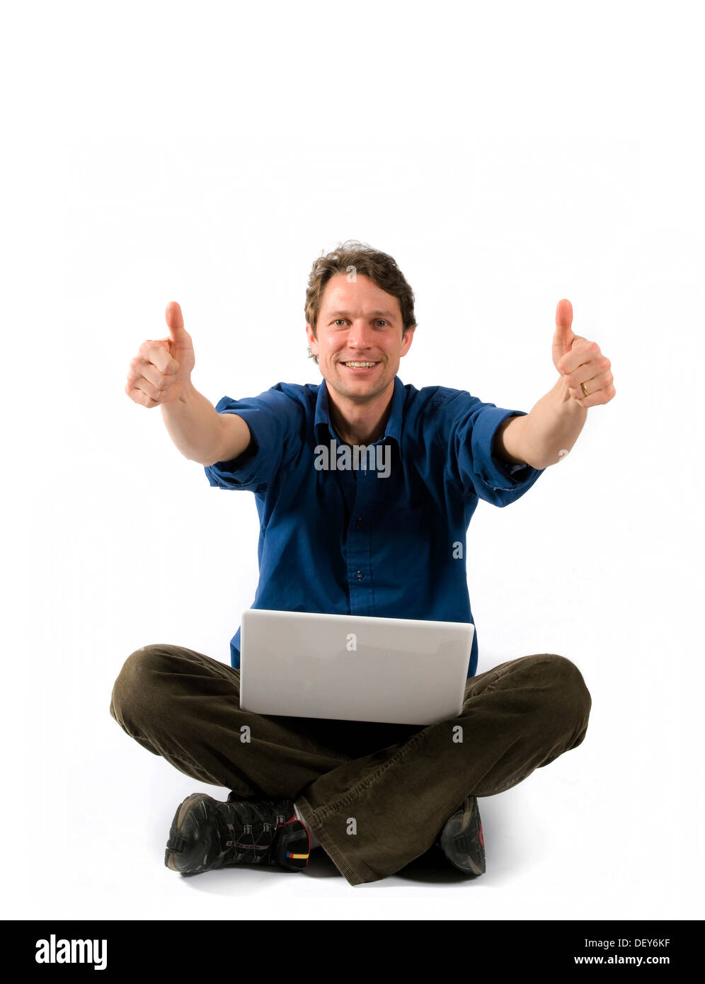 Cheering man with laptop sitting cross-legged Stock Photo
