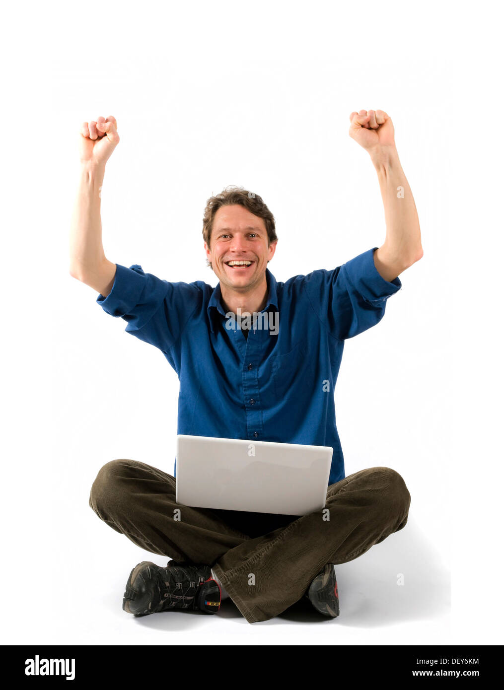 Cheering man with laptop sitting cross-legged Stock Photo