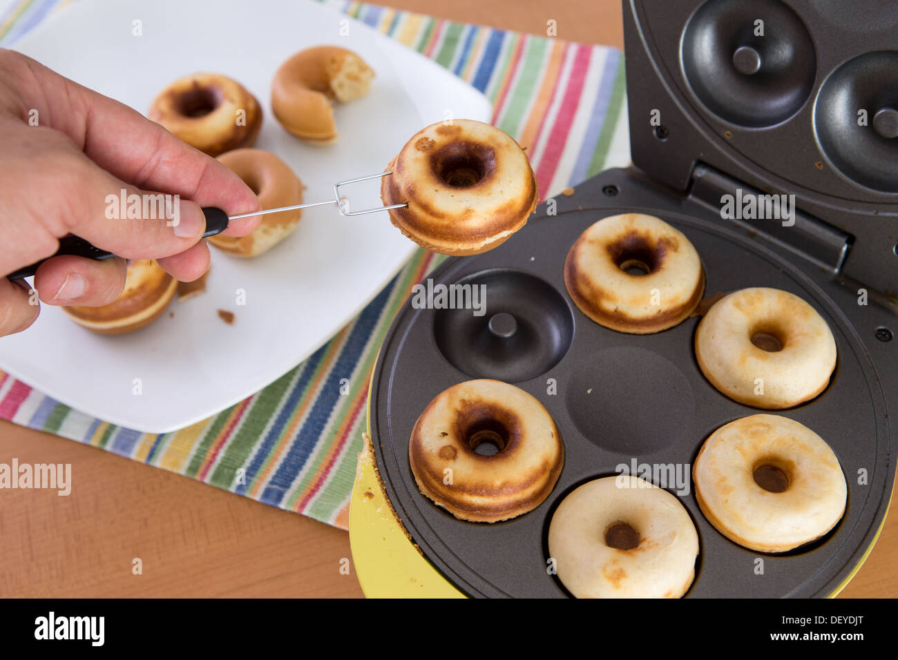 Clean hands baking mini donuts in the donut making machine Stock Photo