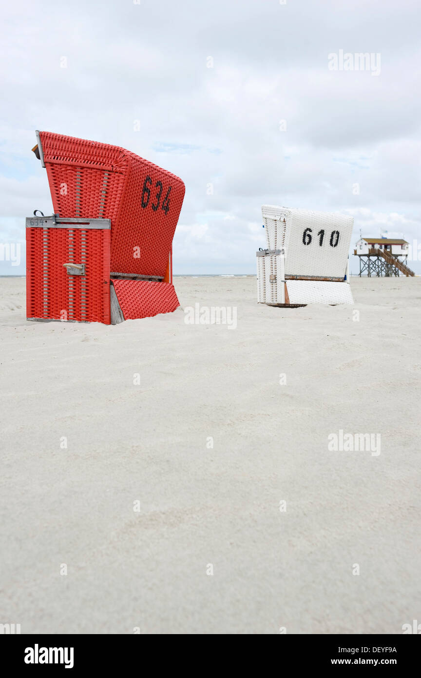 View of Roofed wicker beach chairs on the beach in front of a house on stilts ...