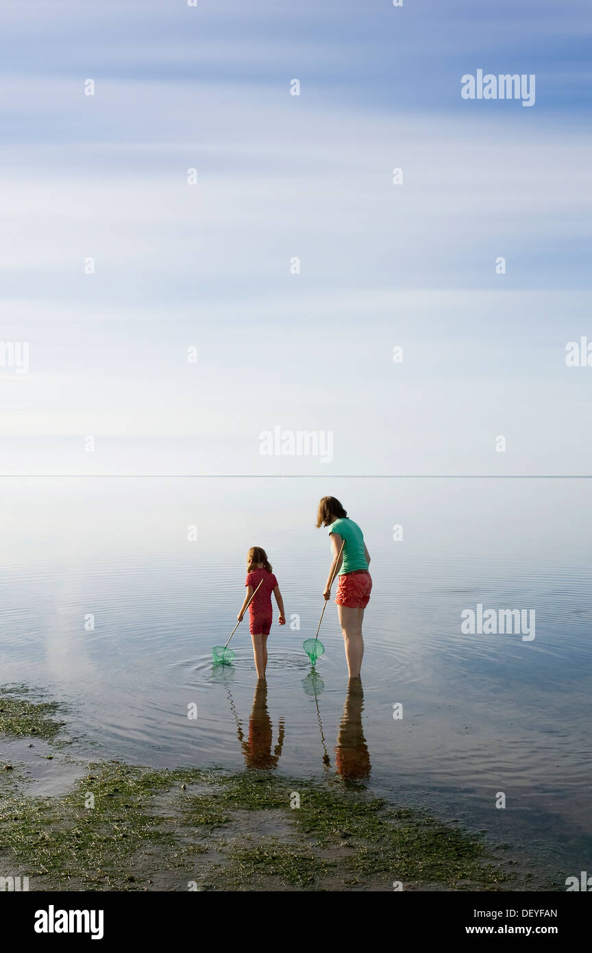Woman and girl with dip nets standing in the Wadden Sea, Wyk, Föhr, Schleswig-Holstein, Germany Stock Photo