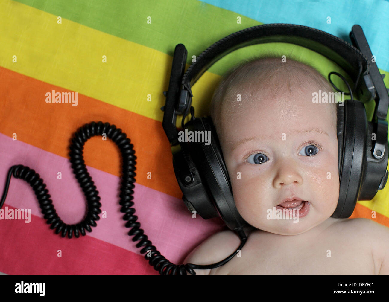 Baby girl listening to music on headphones.  Baby wearing headphones. Stock Photo