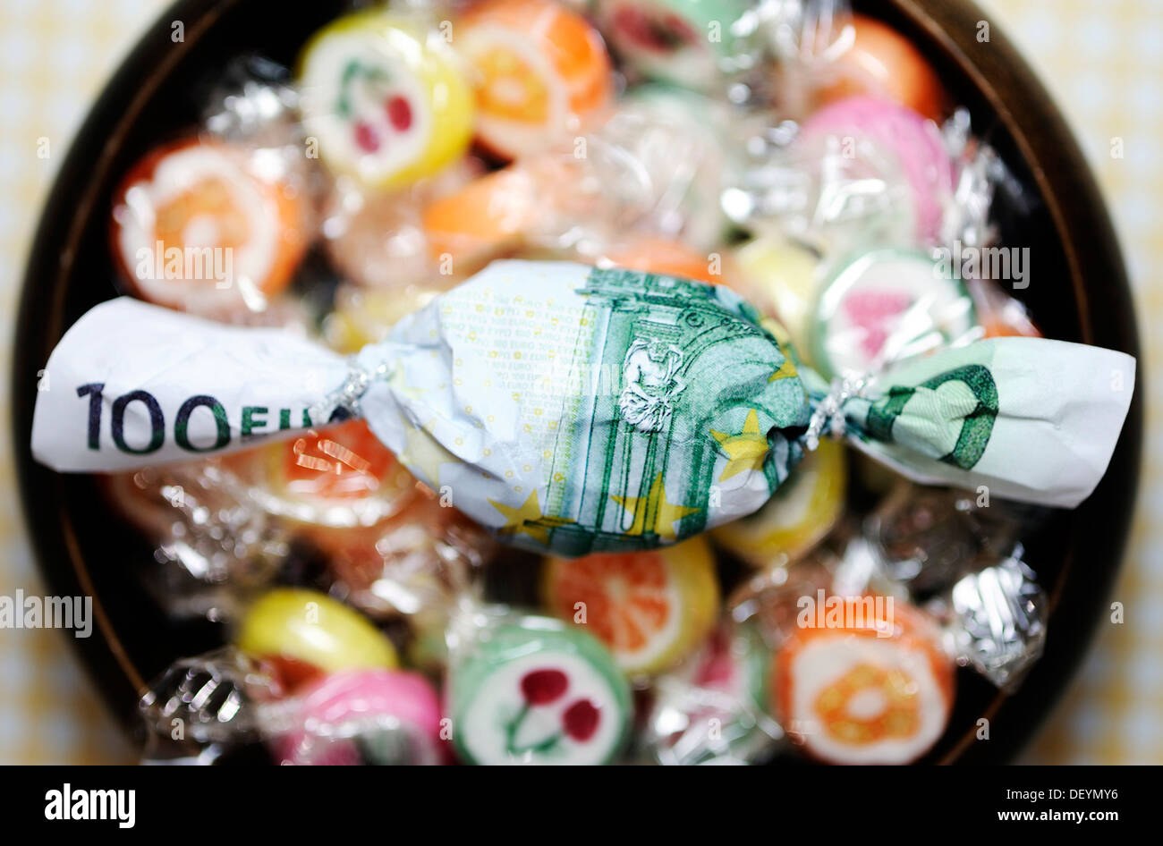 Candy wrapped in a hundred-euro bill, symbolic image for premiums Stock Photo