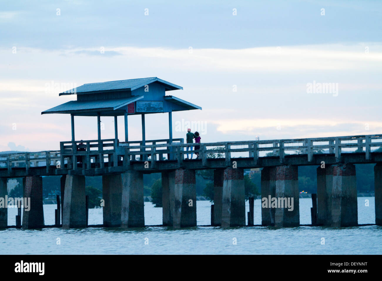 People walk across U Bein's Bridge at sunset on Taungthaman Lake ...