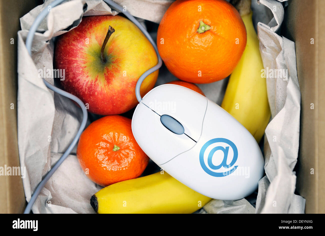 Parcel with fruit and a computer mouse, symbolic image for online grocery shopping Stock Photo