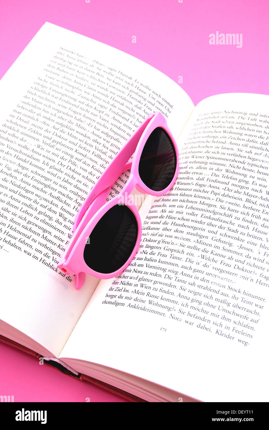 Pink sunglasses serving as a bookmark, open book Stock Photo