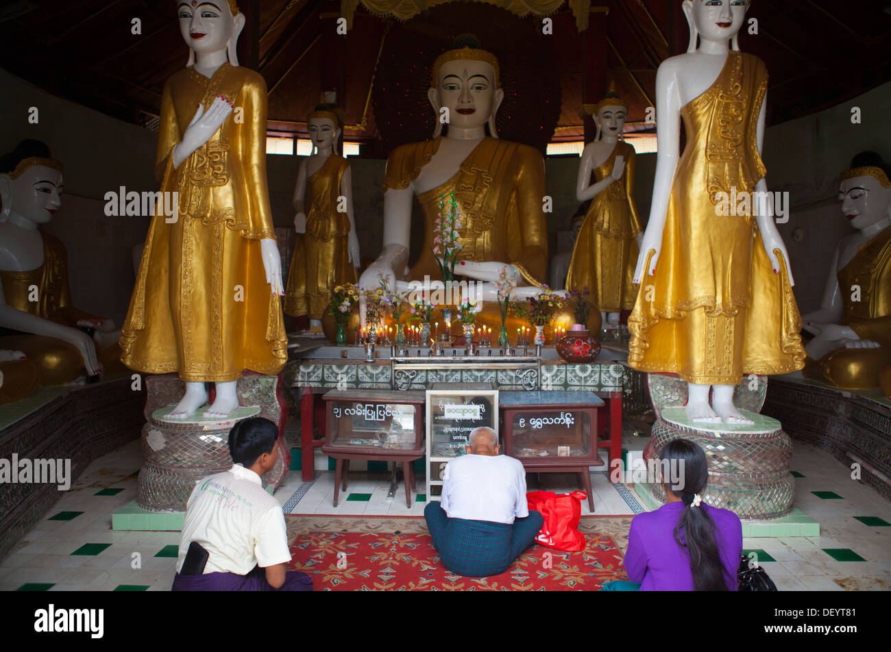 People pray in front of buddha statues at U Zina Paya in Mawlamyine. Stock Photo