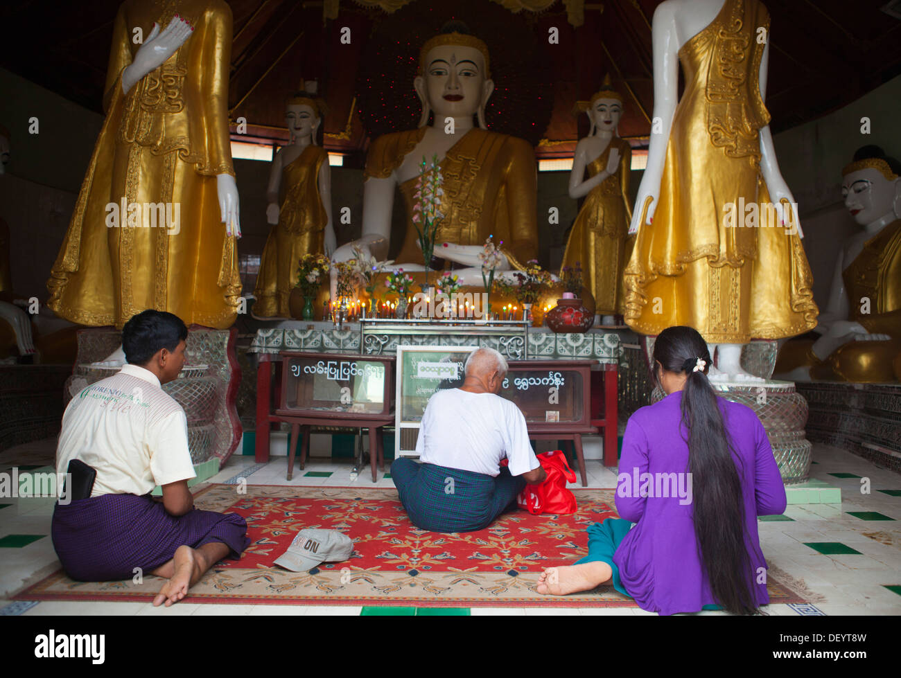 People pray in front of buddha statues at U Zina Paya in Mawlamyine. Stock Photo
