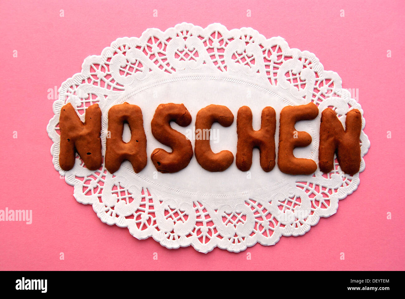 Lettering 'Naschen', German for 'eating sweets', lettering, alphabet biscuits on a cake lace coaster Stock Photo