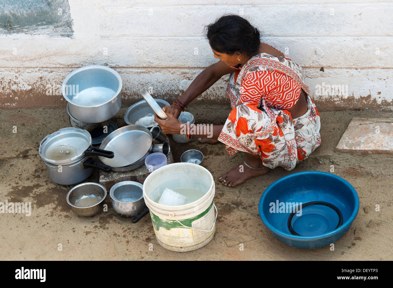 Indian woman washing dishes outside their rural indian village home. Andhra Pradesh, India Stock Photo