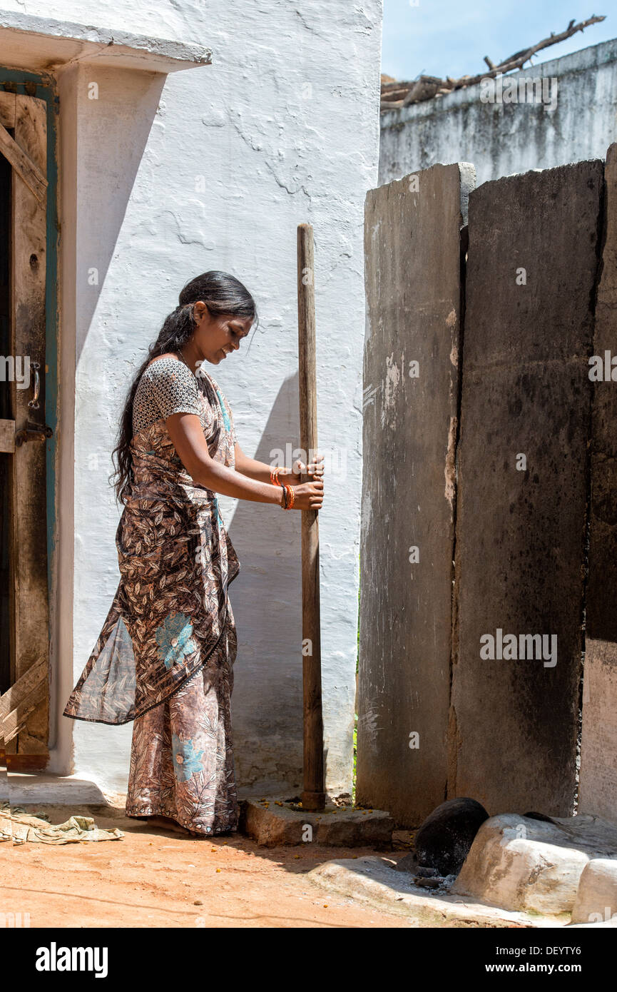 Indian woman crushing turmeric roots to powder in a rural Indian village. Andhra Pradesh, India Stock Photo
